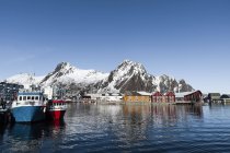Fishing boats in harbour and snowcapped mountains — Stock Photo