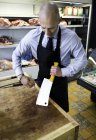 Butcher cleaning meat cleaver in butcher's shop — Stock Photo