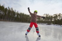 Junge balanciert beim Schlittschuhlaufen auf zugefrorenem See — Stockfoto