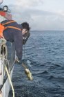Рыбак вытаскивает рыбу на рыбацкую лодку — стоковое фото