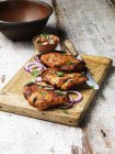 Barbecued tandoori chicken thighs with salad on chopping board — Stock Photo