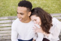 High angle view of young couple sitting on park bench smiling — Stock Photo