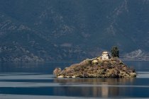 Vista de la casa en la parte superior de la pequeña isla en el lago Lugu al atardecer, Yunnan, China - foto de stock