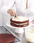 Image recadrée de femme faisant gâteau au chocolat avec de la crème — Photo de stock