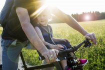Father and baby daughter riding bike together, mid section — Stock Photo