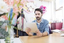 Jeune designer masculin lisant tablette numérique dans le studio de presse à imprimer — Photo de stock