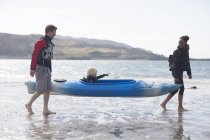 Родители несут сына в каноэ на пляже, Лох-Эйшорт, остров Скай, Гебриды, Шотландия — стоковое фото