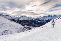 Человек, идущий по заснеженной горе, вид сзади, Энгадин, Швейцария — стоковое фото
