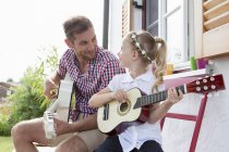 Девушка играет на гитаре с отцом — стоковое фото