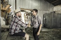 Dos científicos estrechando la mano en el granero del centro de investigación de crecimiento vegetal - foto de stock