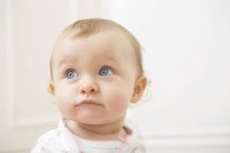 Portrait de bébé fille à la maison, expression curieuse — Photo de stock