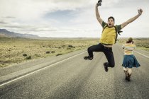 Молодой человек в стиле ретро, прыгающий в воздухе на дороге, Коди, Вайоминг, США — стоковое фото