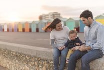 Young family sitting on beach wall — Stock Photo