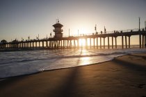 Silhouetted view of pier at sunset, Huntington Beach, California, USA — Stock Photo