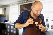 Male barista stirring coffee glass in coffee bar — Stock Photo