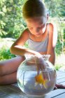 Молода дівчина з пальцями в мисці з золотою рибою — стокове фото