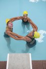 Portrait of three schoolgirl swimmers making circle — Stock Photo