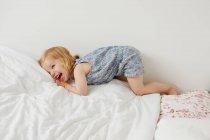 Lindo niño femenino jugando en la cama - foto de stock
