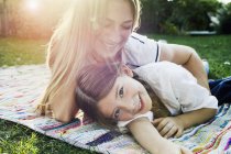 Mother and daughter lying on rug in garden — Stock Photo