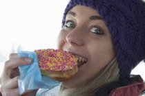 Молода жінка кусає пончик — стокове фото