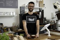Retrato del camarero de café sirviendo café del mostrador - foto de stock