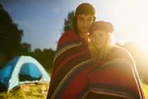 Retrato de casal acampamento jovem romântico envolto em cobertor ao pôr do sol — Fotografia de Stock