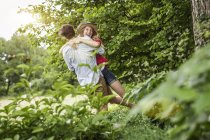 Jovem casal abraçando e rindo no jardim — Fotografia de Stock