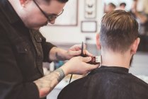 Парикмахер с ножницами на шее клиента в парикмахерской — стоковое фото