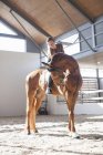Mulher adulta média no cavalo castanho no pórtico interior — Fotografia de Stock