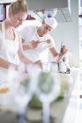 Chefs masculinos y femeninos cocinando en la cocina comercial - foto de stock