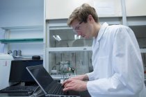 Cientista do sexo masculino digitando no laptop no laboratório — Fotografia de Stock