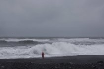 Homme sur la plage regardant les vagues de la mer, Vik, Islande — Photo de stock
