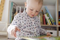 Жіночий малюк читає книгу в ігровій кімнаті — стокове фото