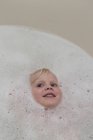 Retrato de niña angelical cara en baño de burbujas - foto de stock