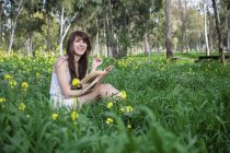Молода жінка сидить у лісі, читає книгу — стокове фото