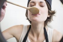 Female chef tasting food from saucepan in commercial kitchen — Stock Photo