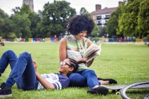Мальчик и мать отдыхают и читают книгу в парке — стоковое фото