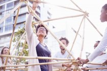 Low angle view of colleagues in team building task building wooden structure — Stock Photo
