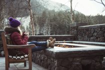 Jovem mulher sentada no banco com fogueira, Girdwood, Anchorage, Alaska — Fotografia de Stock