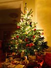 Árvore de Natal iluminada com presentes embaixo — Fotografia de Stock