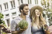 Cute couple with watermelon laughing while walking in garden — Stock Photo