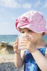Femme tout-petit eau potable sur la plage — Photo de stock