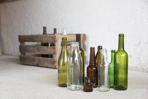 Разнообразие пустых бутылок и деревянного ящика в гараже — стоковое фото