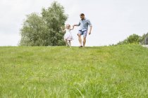 Père et fille en descente avec prairie verte — Photo de stock