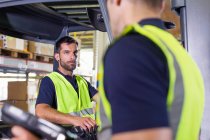 Supervisore che istruisce il conducente del carrello elevatore nel magazzino di distribuzione — Foto stock