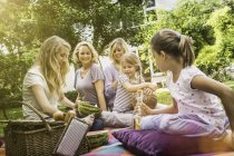 Tres generaciones de mujeres haciendo picnic en el jardín - foto de stock