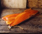 Raw smoked salmon with skin on rustic wooden table — Stock Photo