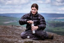 Молода жінка мандрівного відкриття flask на вершині виглядом Скеля, Pateley міст, Nidderdale, Йоркшир землі — стокове фото