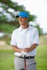 Golfista usando luva de golfe e boné de beisebol segurando clube de golfe olhando para longe sorrindo — Fotografia de Stock