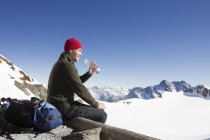 Male hiker drinking water on viewing platform, Jungfrauchjoch, Grindelwald, Switzerland — Stock Photo